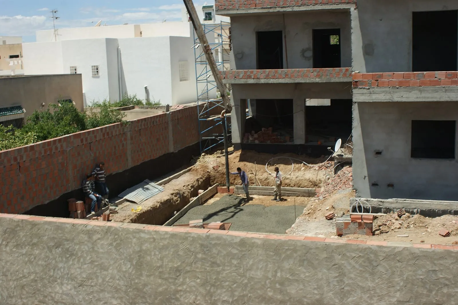 Coulage du béton sur les fondations d'une piscine en construction