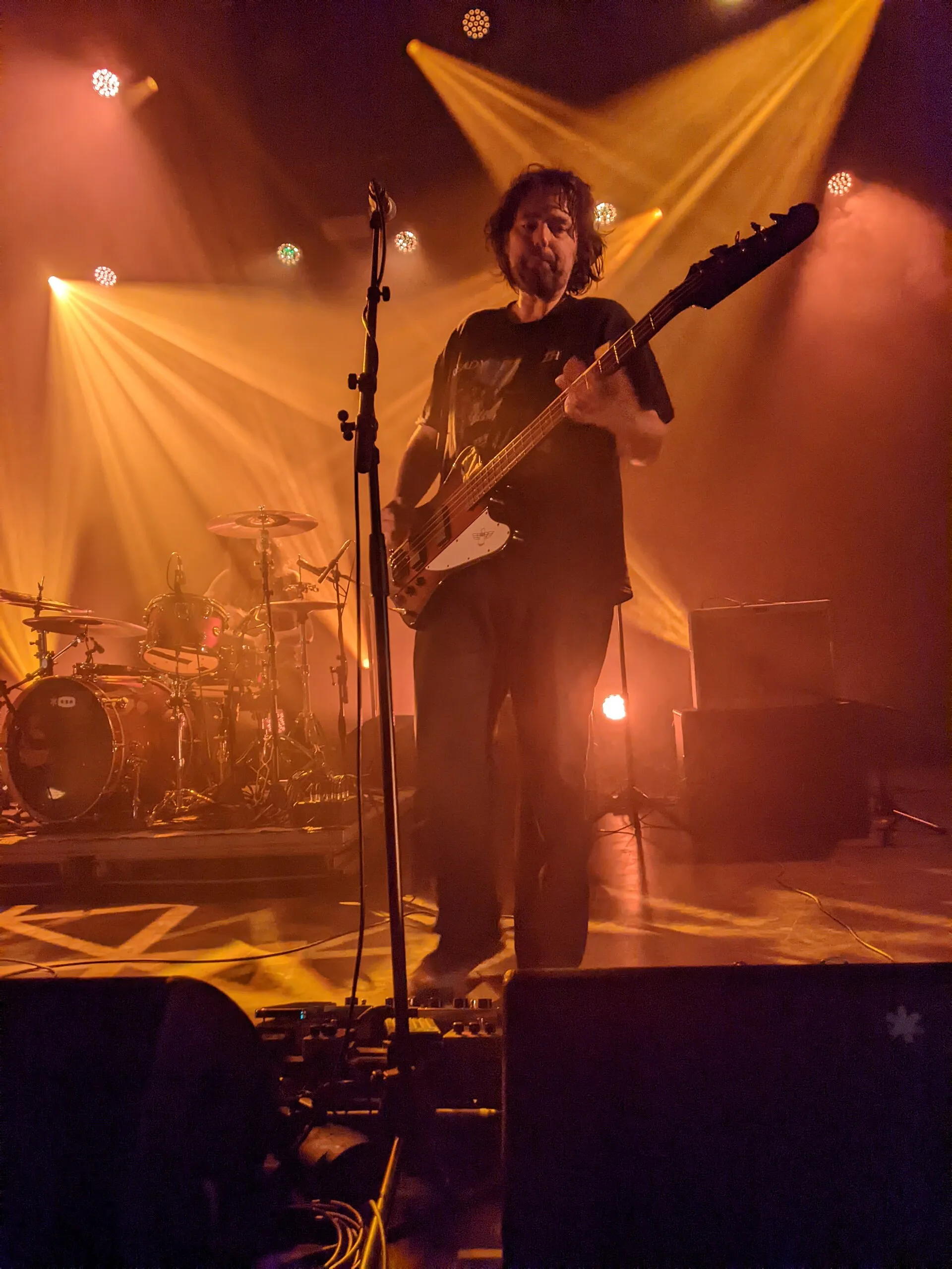Un bassiste sur scène pendant un concert, sous l'éclairage de scène