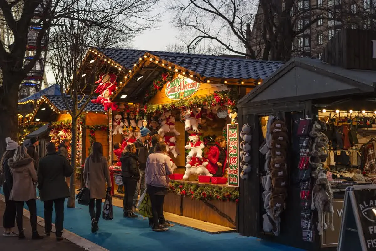 Chalets en bois et guirlandes lumineuses d'un marché de Noël, en fin de journée