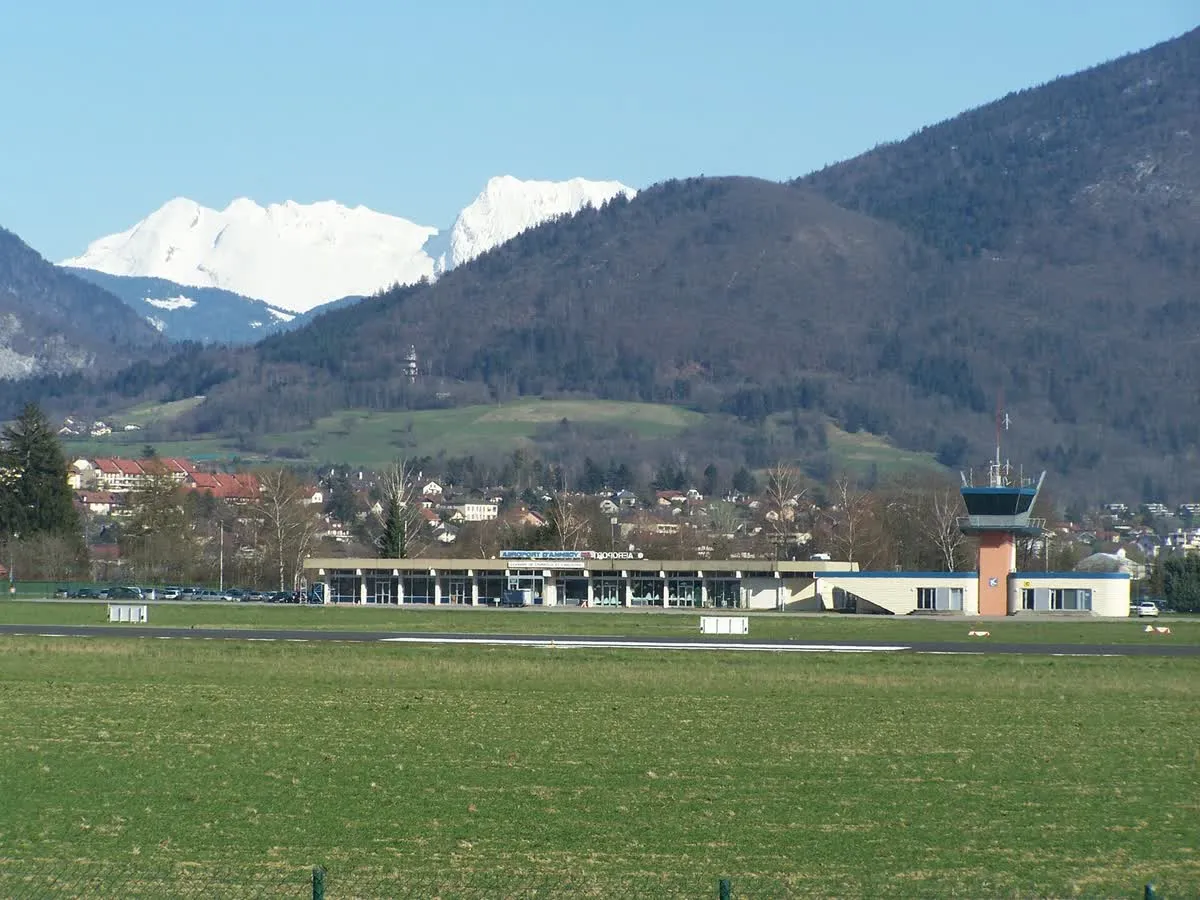 Le terminal et la tour de contrôle de l'aéroport Annecy Haute-Savoie Mont-Blanc, à Meythet, avec les sommets enneigés en arrière-plan