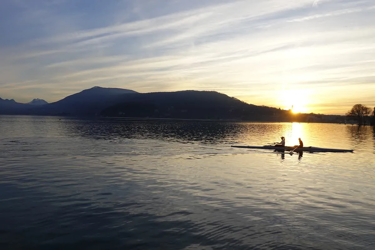 Deux rameurs sur le lac d'Annecy au coucher du soleil, devant les montagnes